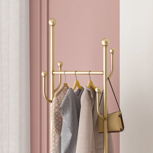 Golden metal cactus coat rack with side hooks holding patterned garments and handbag
