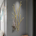 Gold metal branch coat rack with patterned scarf in modern hallway setting