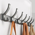 Close-up of dark grey six-hook metal rack with orange bag strap and knitwear