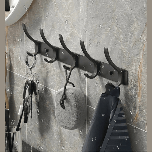 Black metal coat rack with five hooks holding keys and shirt in wet bathroom