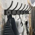 Black 6-hook aluminum coat rack with flat backplate holding striped garment and sponge